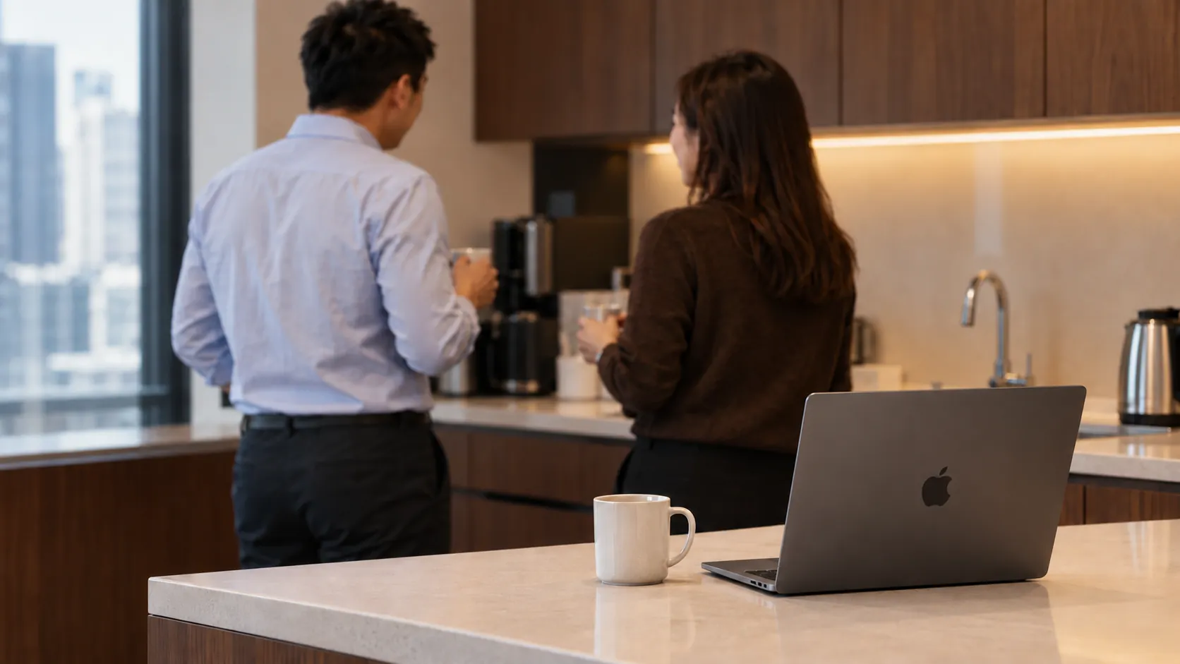 Two colleagues chatting over coffee in an office pantry